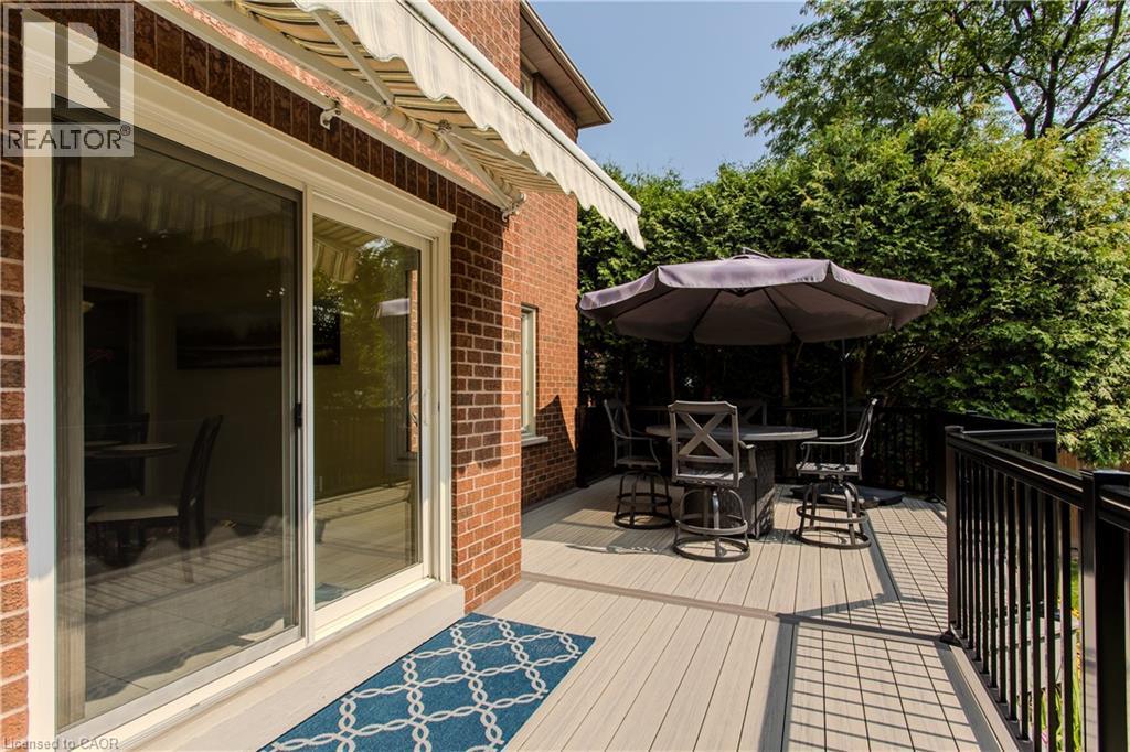 Composite decking with black metal railings, a retractable awning, and a brick exterior - 1238 Sable Drive, Burlington, ON - Outdoor With Deck Patio Veranda With Exterior