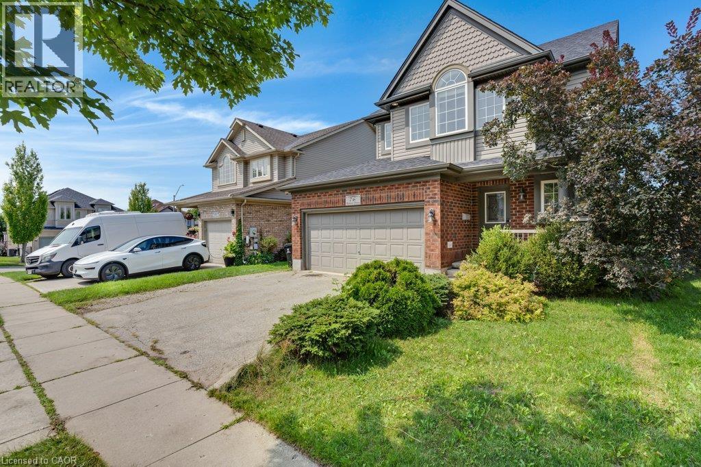 Brick and siding exterior with an integrated garage, arched window, and mature landscaping - 76 Renner Drive, Cambridge, ON - Outdoor With Facade