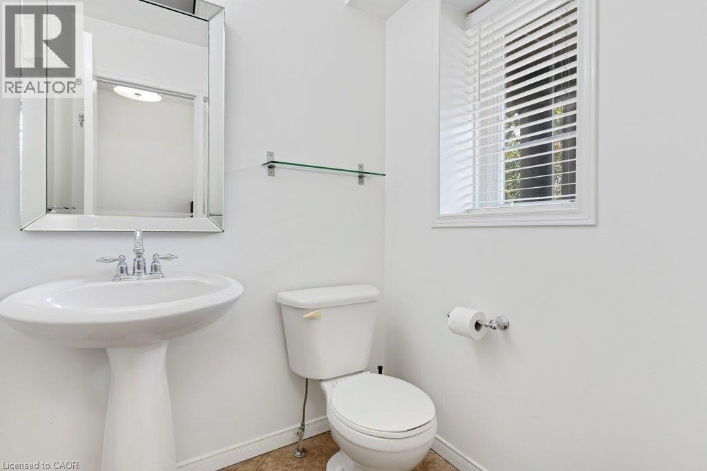 Pedestal sink with chrome fixtures, reflective framed mirror, glass shelf, and a window with blinds - 76 Renner Drive, Cambridge, ON - Indoor Photo Showing Bathroom