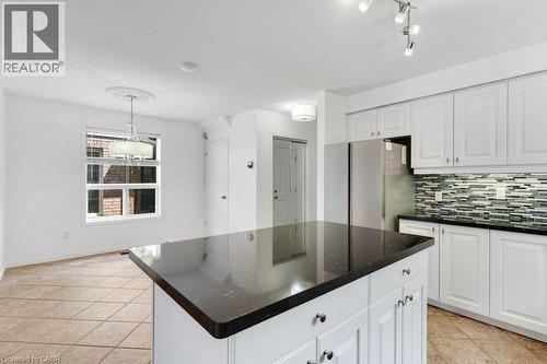 Kitchen featuring a central island with a dark countertop, white cabinetry with gold-tone hardware, and a mosaic tile backsplash - 76 Renner Drive, Cambridge, ON - Indoor Photo Showing Kitchen With Upgraded Kitchen