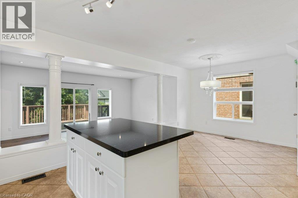 Kitchen island with dark countertop, white cabinetry, and polished hardware - 76 Renner Drive, Cambridge, ON - Indoor