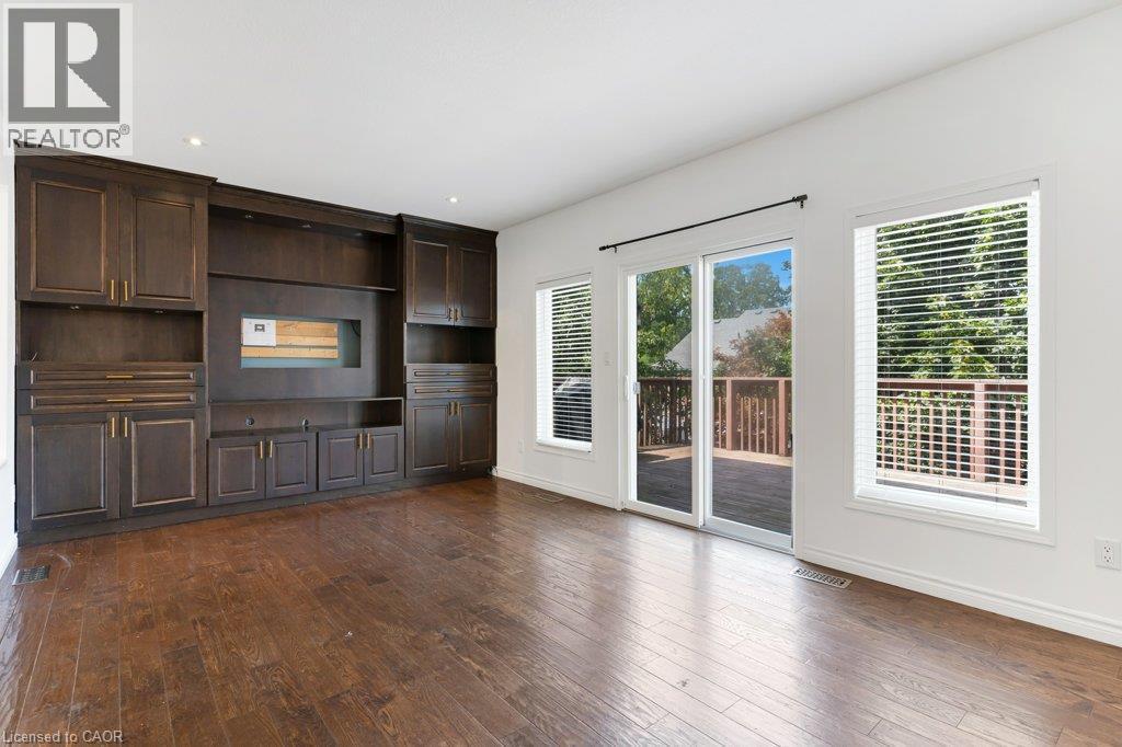 Built-in cabinetry with dark wood finish, hardwood flooring, recessed lighting, sliding glass door, and large windows with blinds - 76 Renner Drive, Cambridge, ON - Indoor