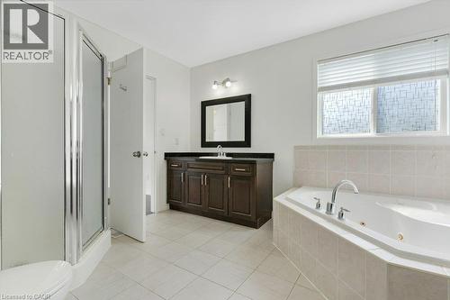 Spacious bathroom featuring a glass-enclosed shower, a large soaking tub, a dark wood-finish vanity with an undermount sink, and tiled flooring - 76 Renner Drive, Cambridge, ON - Indoor Photo Showing Bathroom