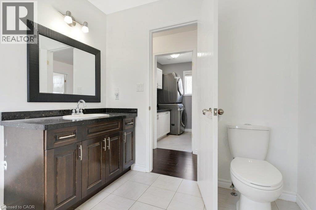 Bathroom featuring a dark wood-finish vanity with an undermount sink, dark countertop, and a framed mirror - 76 Renner Drive, Cambridge, ON - Indoor Photo Showing Bathroom