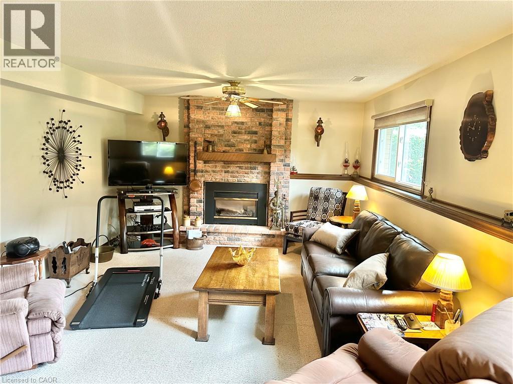 Brick-surround fireplace with a wood mantle, ceiling fan, carpeted flooring, - 44 Douglas Avenue, Simcoe, ON - Indoor Photo Showing Living Room With Fireplace