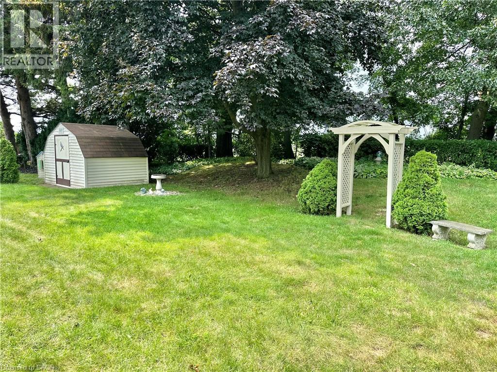 Expansive backyard featuring a storage shed, landscaped arbor, and mature trees - 44 Douglas Avenue, Simcoe, ON - Outdoor