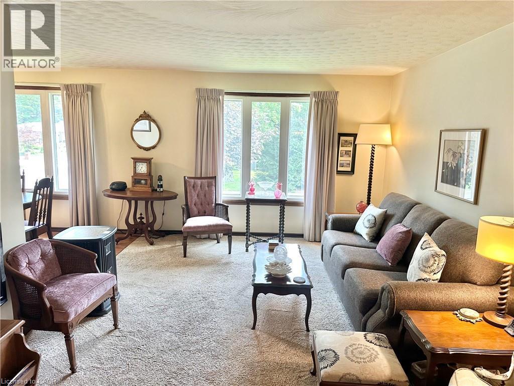 Living Room Wall-to-wall carpeting in a neutral tone, multiple windows with neutral drapery, and painted walls in a light hue - 44 Douglas Avenue, Simcoe, ON - Indoor Photo Showing Living Room