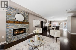Stacked stone fireplace with a wood mantel, dark wood-finish flooring, recessed lighting, and a defined open concept layout - 