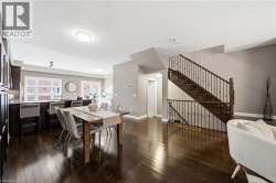 Dark wood-finish flooring throughout, prominent staircase with dark wood treads and balusters, kitchen island with counter seating, sliding glass door, and recessed lighting - 