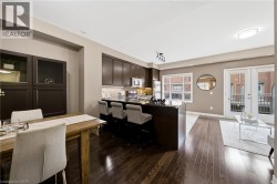 Open-concept living space featuring dark wood cabinetry, stainless steel appliances, and wood-finish flooring throughout - 