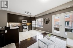 Kitchen featuring dark wood-finish cabinetry, stainless steel appliances, and a mosaic tile backsplash - 