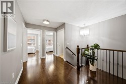Hallway featuring wood-finish flooring, two doorways, a chandelier, and a wood and wrought iron railing - 