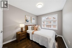 Cozy bedroom featuring warm wood-finish flooring, soft neutral wall tones, and abundant natural light from a multi-pane window - 