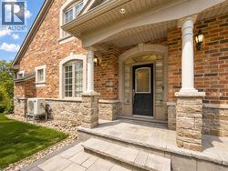 Brick and stone exterior with arched window details, a covered entry, and sconce lighting - 