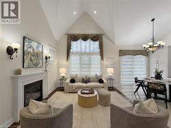Vaulted ceilings with recessed lighting, integrated fireplace, dark wood-finish flooring, and a chandelier-lit dining area - 
