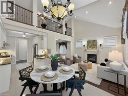 Vaulted ceiling with decorative chandelier, fireplace with white mantel, kitchen with white cabinetry and dark countertops, wood-finish flooring, and open railing overlooking the living space - 