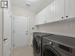 White shaker-style cabinetry with black hardware, utility sink, and tile flooring - 