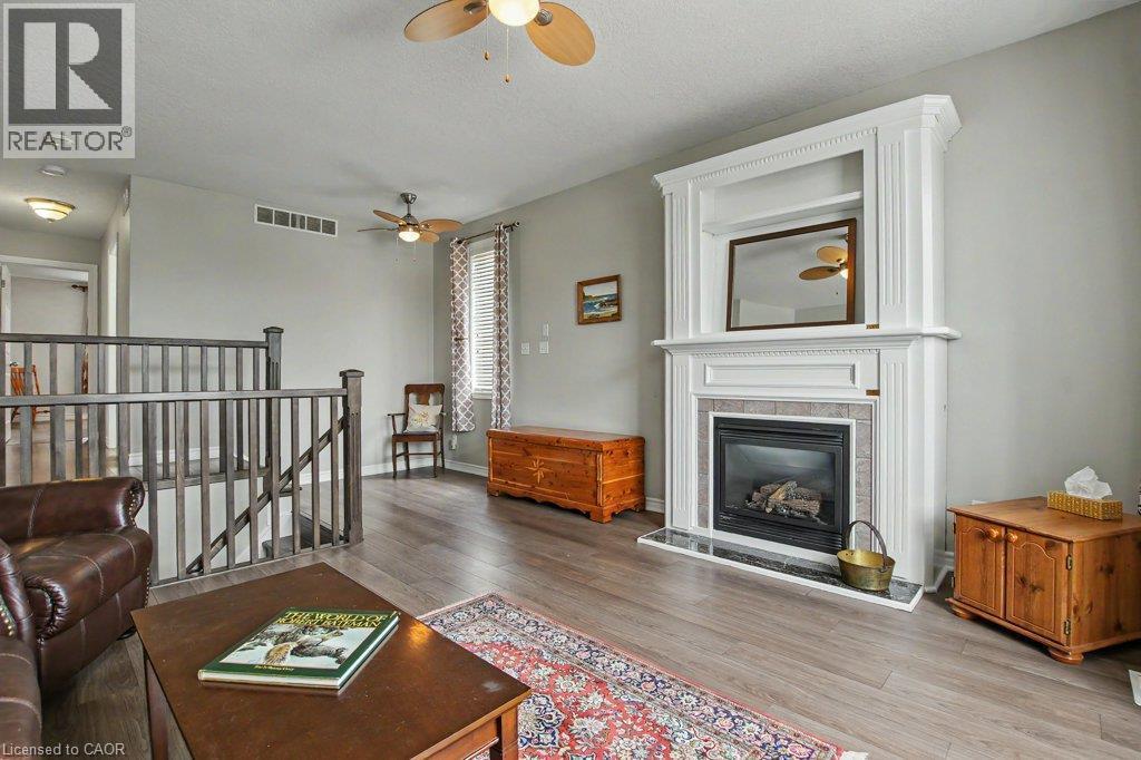 Fireplace with detailed white mantel and tile surround, wood flooring, open staircase with wood railings - 568 Robert Ferrie Drive, Kitchener, ON - Indoor Photo Showing Living Room With Fireplace