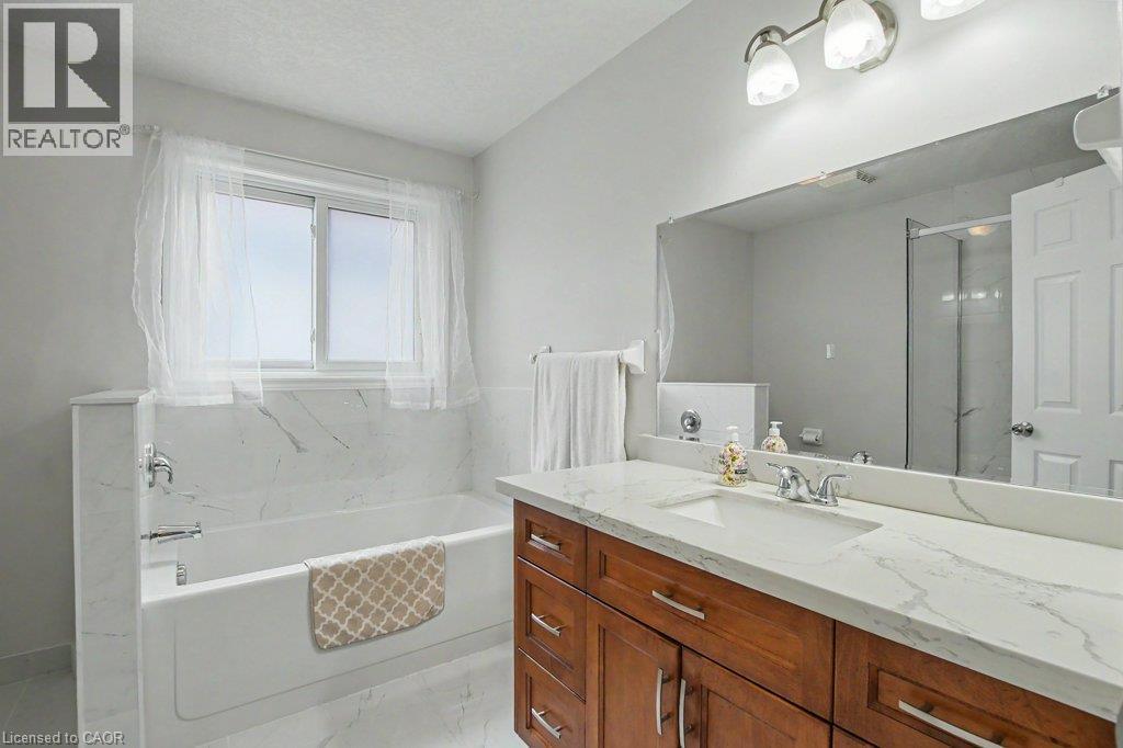 Main bathroom with white soaker tub with marble-finish tile surround - 568 Robert Ferrie Drive, Kitchener, ON - Indoor Photo Showing Bathroom