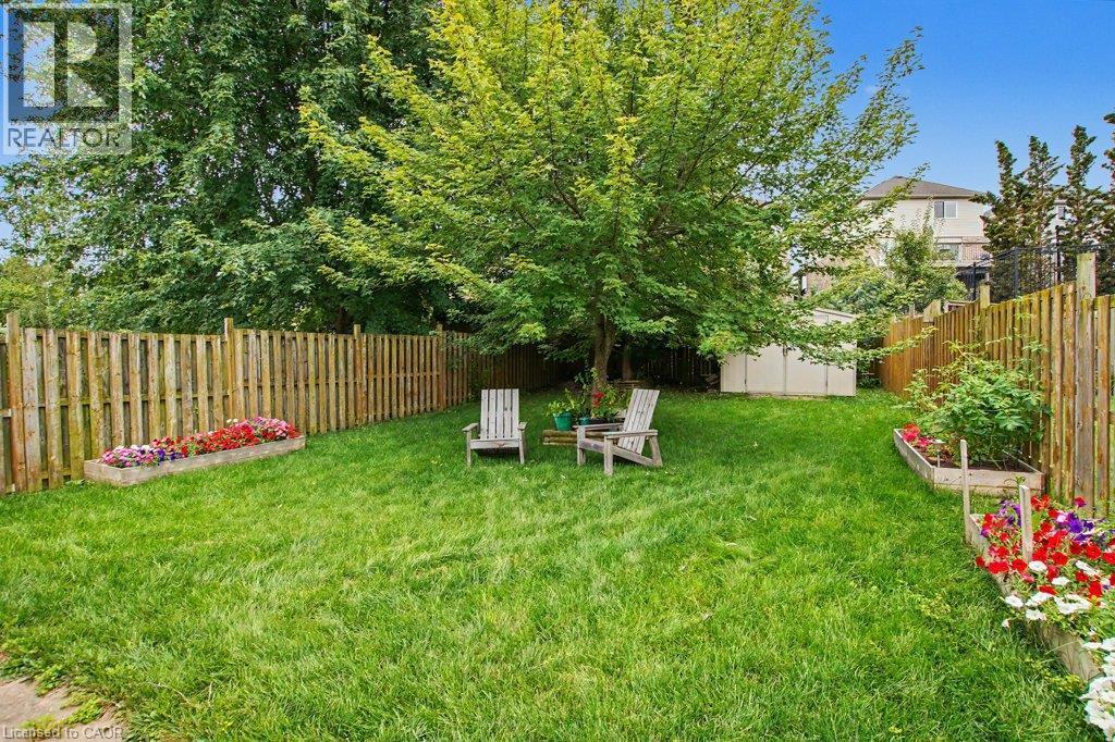 Expansive backyard featuring a manicured lawn, mature trees, and a full privacy fence - 568 Robert Ferrie Drive, Kitchener, ON - Outdoor