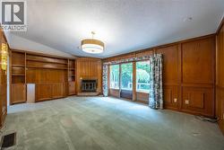 Built-in wood shelving, wood paneling, corner fireplace with brick hearth - 
