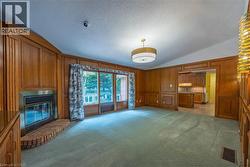 Wood paneling throughout, a built-in fireplace with a brick hearth, wall-to-wall carpeting - 