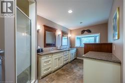 Ensuite with Dual vanity, wood-finish framed mirrors, and wall sconces - 