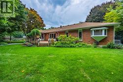 Brick exterior with a multi-level wood deck, fully fenced expansive lawn, and mature trees - 