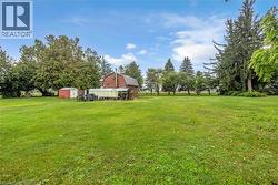 evergreens and deciduous specimens, and a red barn structure with attached outbuildings positioned on the property - 