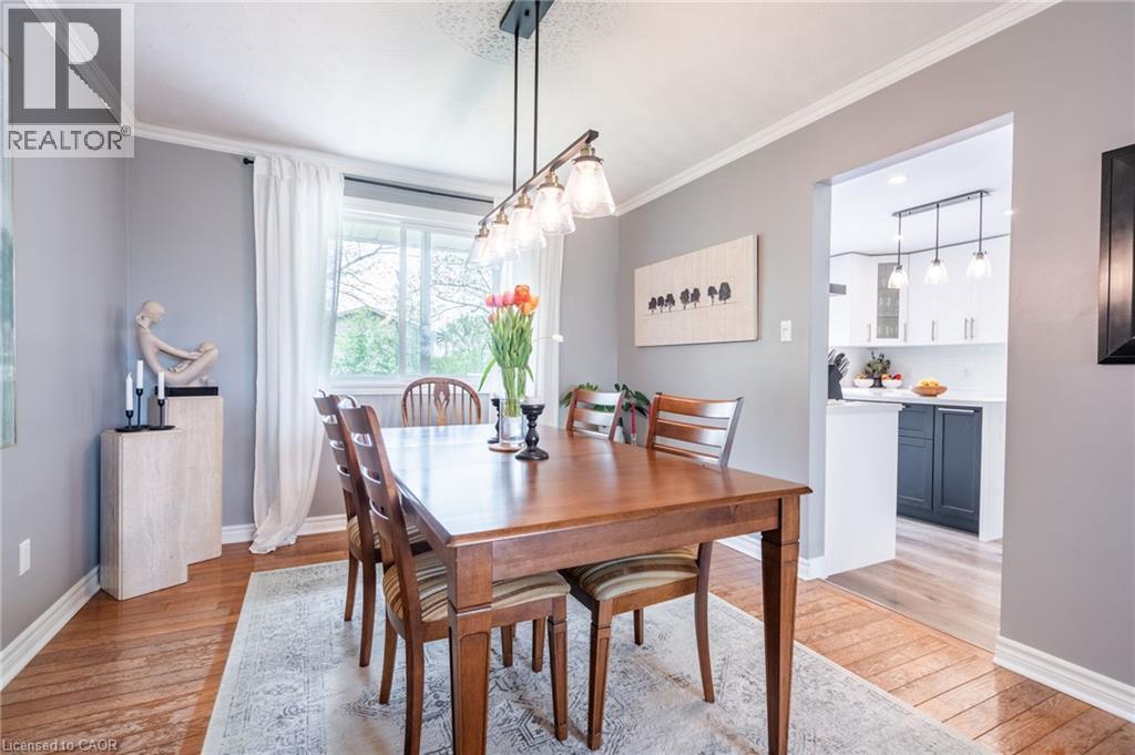 Hardwood-finish flooring, crown molding, modern linear chandelier, window with white curtains, and an open entryway to the kitchen - 152 Concession 7 Road E, Millgrove, ON - Indoor Photo Showing Dining Room