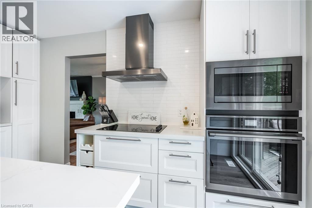 White shaker cabinetry with brushed nickel hardware, stainless steel wall-mounted range hood, built-in microwave, integrated wall oven, and white subway tile backsplash - 152 Concession 7 Road E, Millgrove, ON - Indoor Photo Showing Kitchen With Upgraded Kitchen