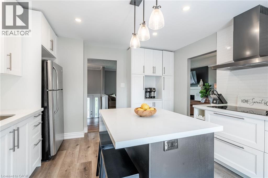 Kitchen featuring white cabinetry, wood-finish flooring, a central island with a light-colored countertop, stainless steel appliances, and a range hood - 152 Concession 7 Road E, Millgrove, ON - Indoor Photo Showing Kitchen With Upgraded Kitchen