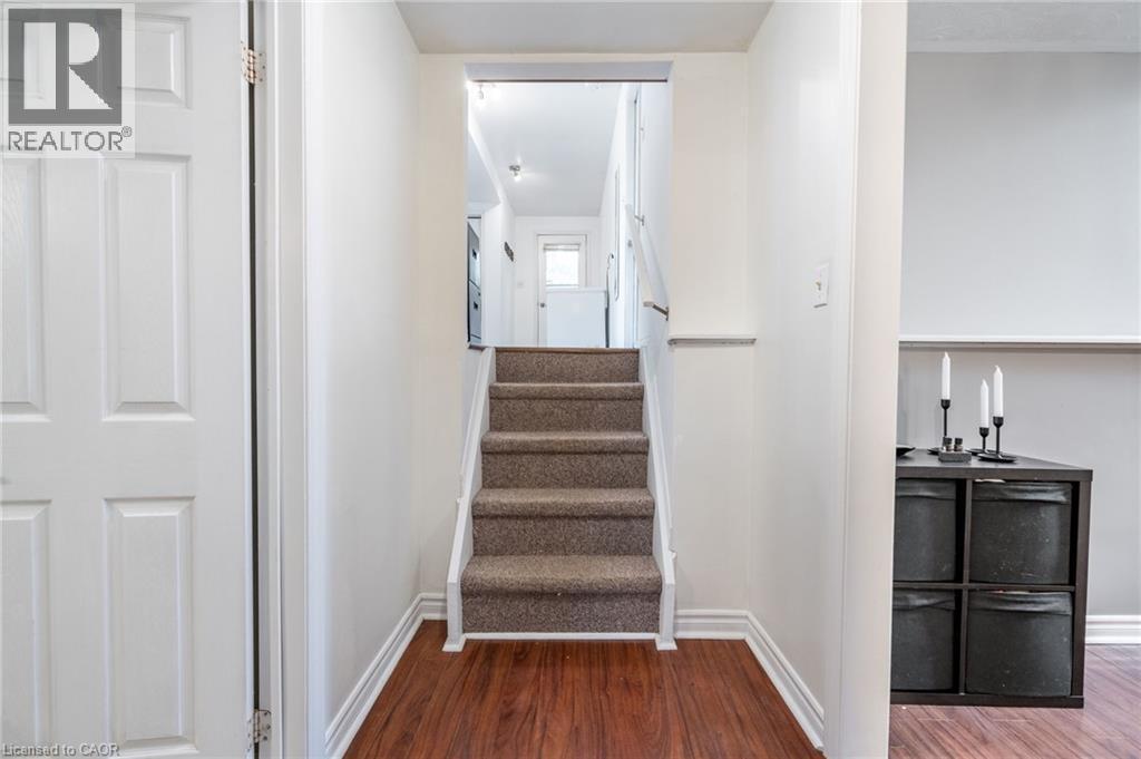 Wood-finish flooring, white paneled door, carpeted staircase, and white wall finishes - 152 Concession 7 Road E, Millgrove, ON - Indoor Photo Showing Other Room