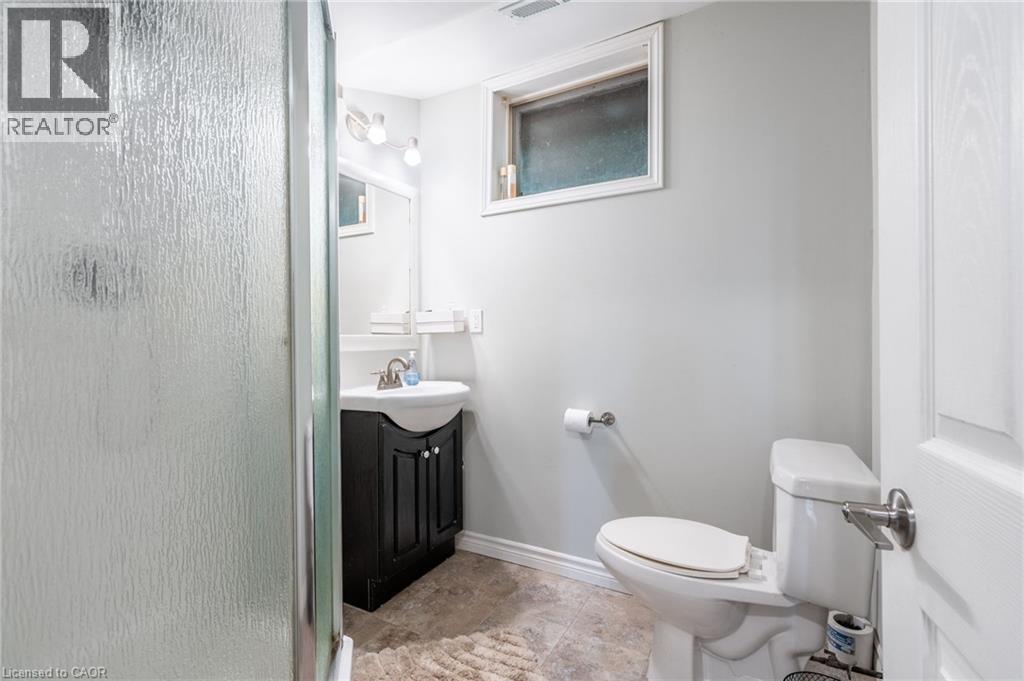 Bathroom featuring a dark wood-finish vanity, white basin sink, polished chrome faucet, and a shower with a textured glass enclosure - 152 Concession 7 Road E, Millgrove, ON - Indoor Photo Showing Bathroom
