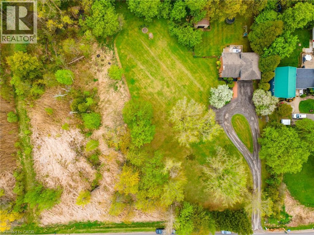 Extensive property featuring a manicured lawn, lush tree coverage, a gravel drive, and a residential structure with a shingled roof - 152 Concession 7 Road E, Millgrove, ON - Outdoor With View