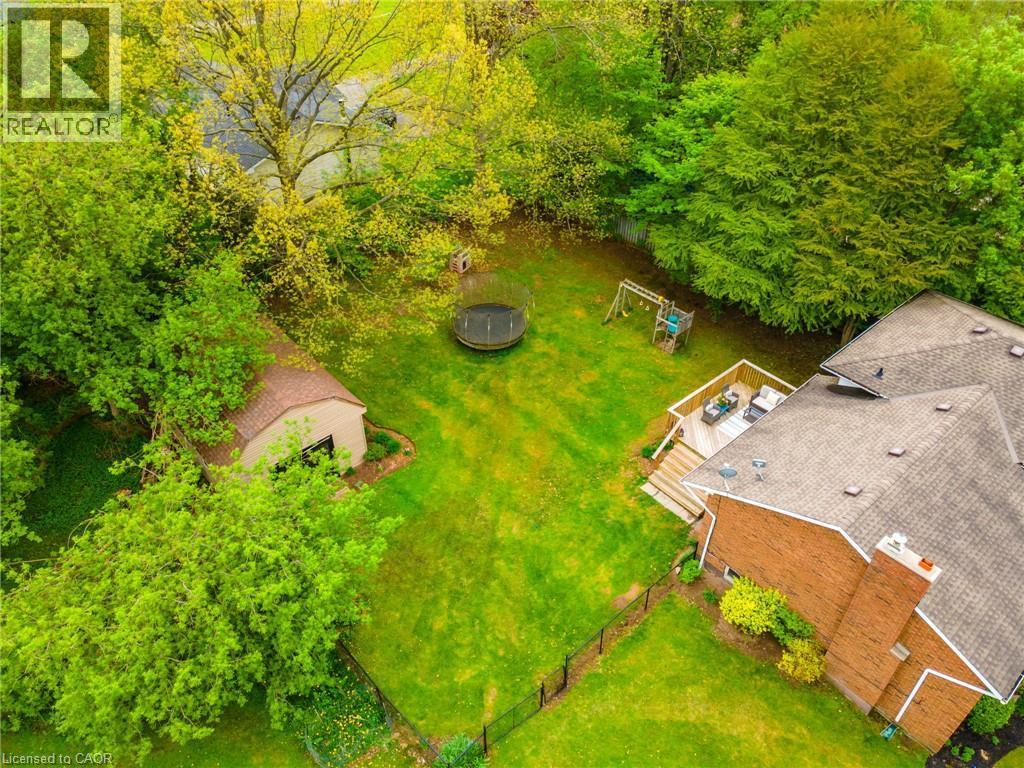 Expansive backyard featuring a manicured lawn, an elevated wood-tone deck, a detached shed, brick exterior, and mature trees - 152 Concession 7 Road E, Millgrove, ON - Outdoor