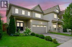 Light-toned siding exterior featuring a covered front porch, an attached garage, and a concrete driveway - 