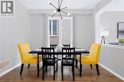 Contemporary chandelier with multiple arms, wood-finish flooring, white trim, and a window with blinds - 