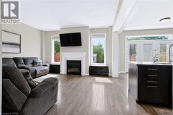 Open-concept living space with wood-finish flooring, a white-mantled fireplace, and white double patio doors - 