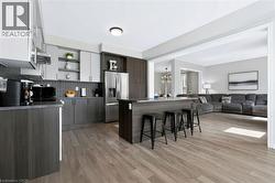 Open-concept kitchen with wood-finish flooring, two-tone cabinetry, and a kitchen island with a countertop - 