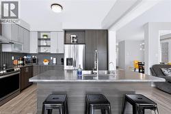 Kitchen featuring a large island with an undermount sink and a wall-mounted faucet - 