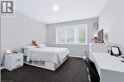 Neutral wall color, recessed window with blinds, overhead flush-mount light fixture, and dark carpet flooring - 