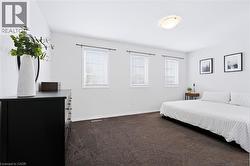 Neutral wall colors, plush carpet flooring, multiple windows with blinds, and an overhead flush-mount light fixture - 