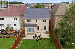 Rear exterior with light-colored siding, a dark shingle roof, and a ground-level patio - 