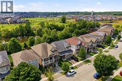 Residential street with detached homes, mature trees, and a natural area featuring a pond - 