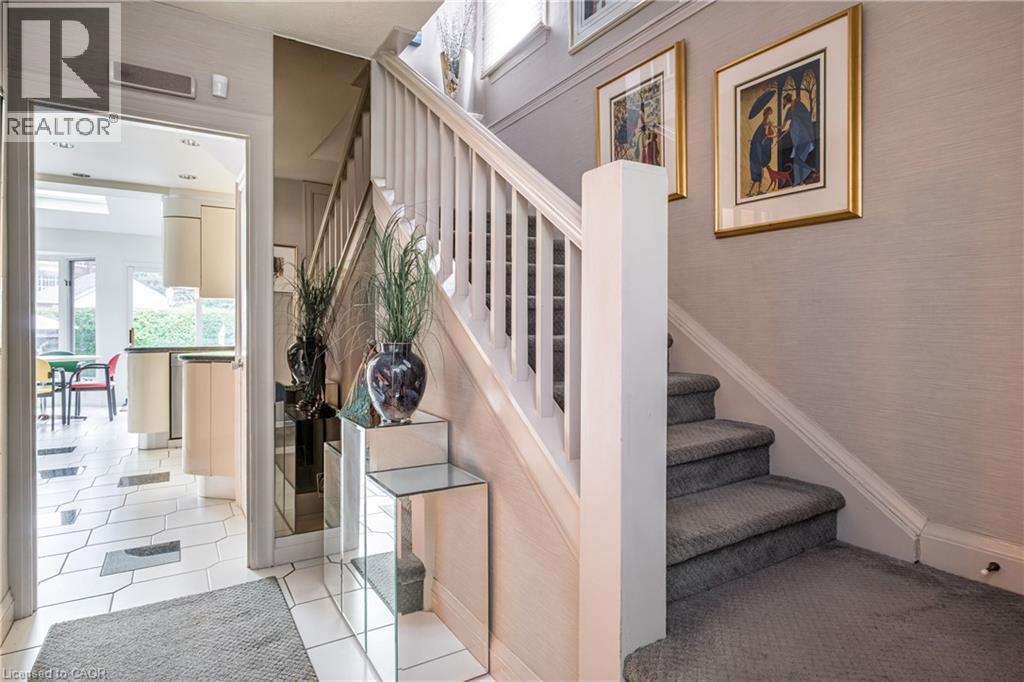 Carpeted staircase with white balusters, textured wall covering, and tiled flooring - 107 Bond Street S, Hamilton, ON - Indoor Photo Showing Other Room