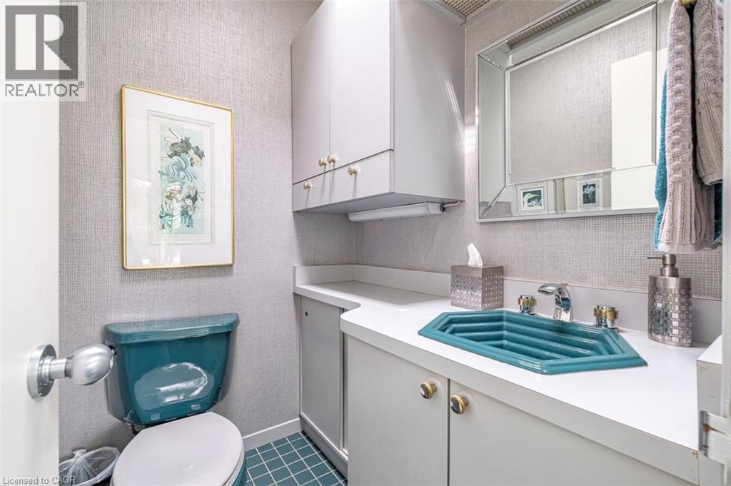 Wall-mounted upper cabinetry, a coordinating vanity with a white countertop, and a uniquely shaped blue basin - 107 Bond Street S, Hamilton, ON - Indoor Photo Showing Bathroom
