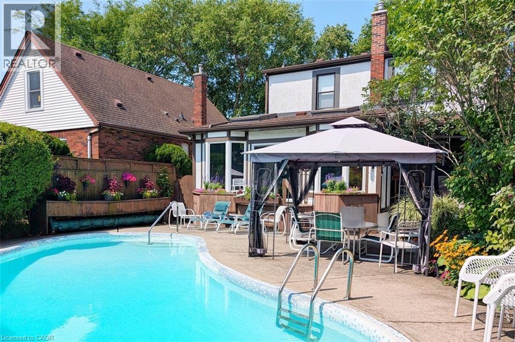 Curved in-ground swimming pool with concrete surround - 107 Bond Street S, Hamilton, ON - Outdoor With In Ground Pool With Deck Patio Veranda