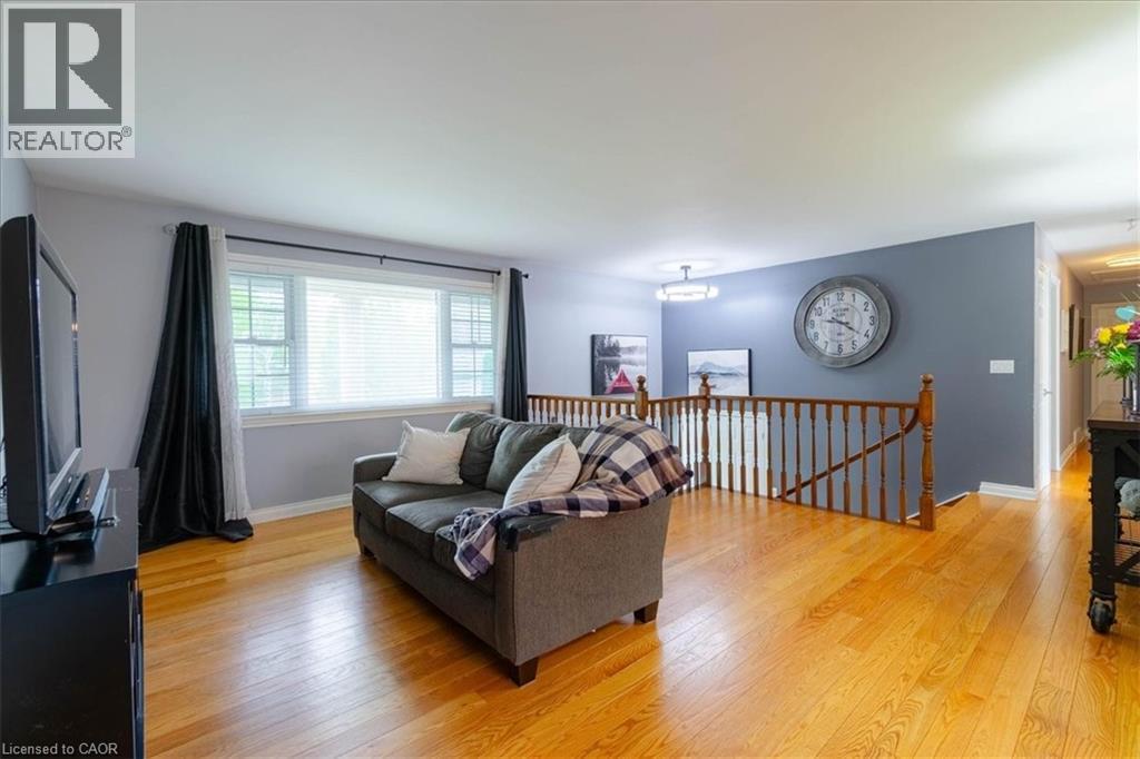 Bright living area featuring wood-finish flooring, a large multi-pane window, and a wood railing - 111 Decou Road, Simcoe, ON - Indoor Photo Showing Living Room