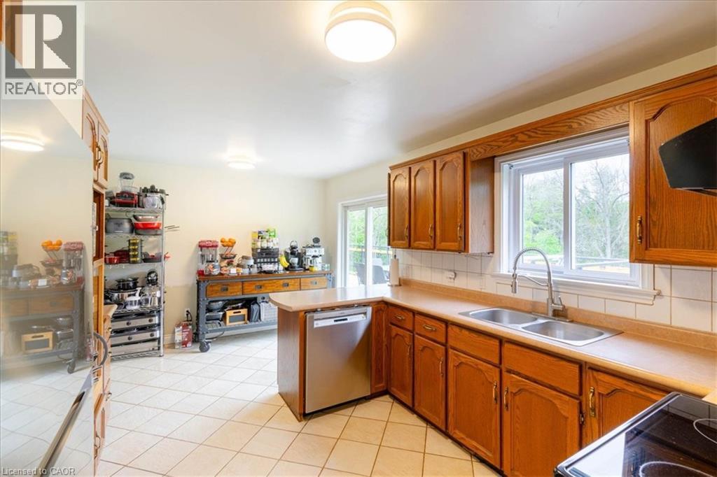 Kitchen featuring wood cabinetry, a stainless steel dishwasher, a double basin sink, and tile flooring - 111 Decou Road, Simcoe, ON - Indoor Photo Showing Kitchen With Double Sink